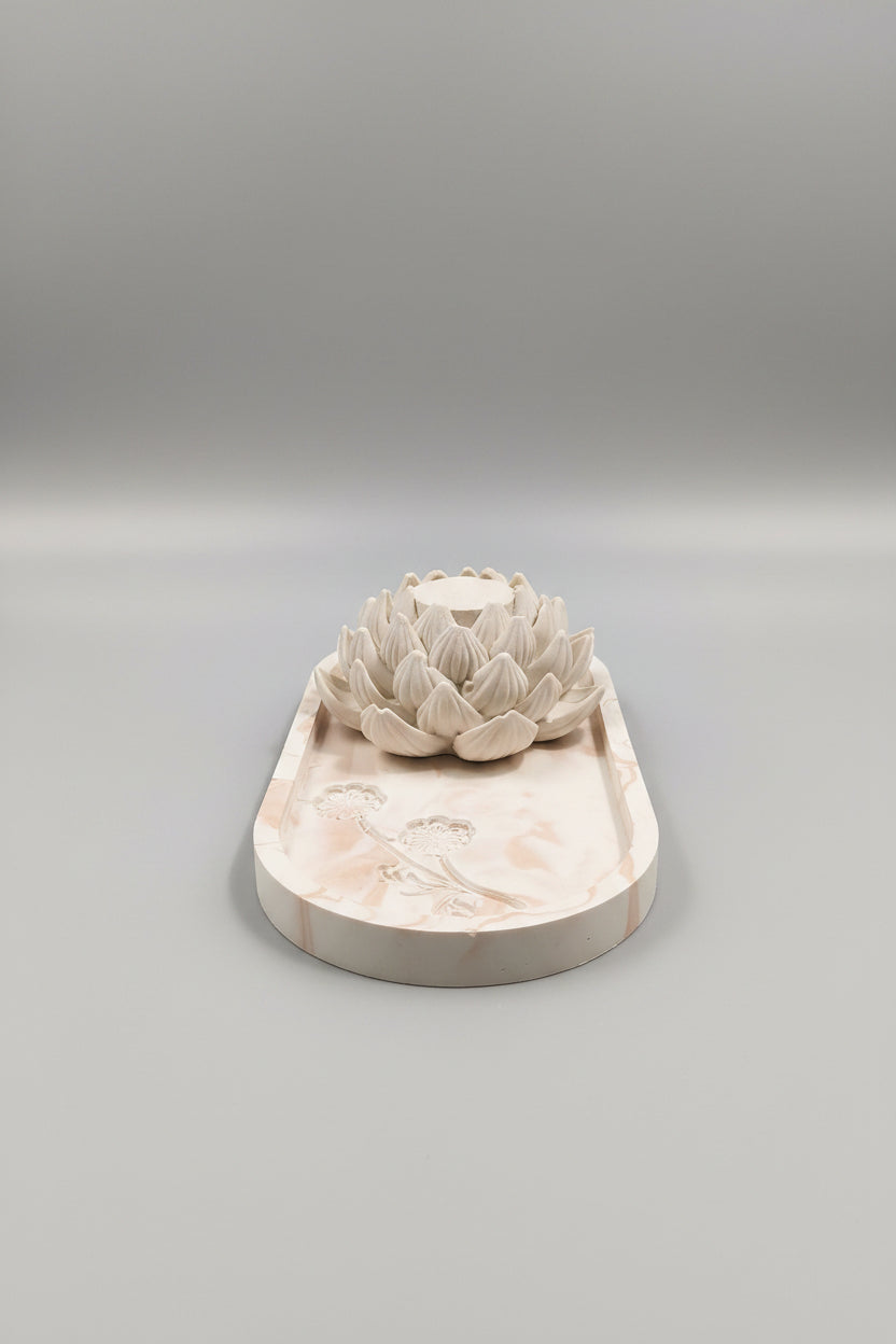 An unglazed ceramic art piece featuring a sculpted lotus flower on an oval tray.