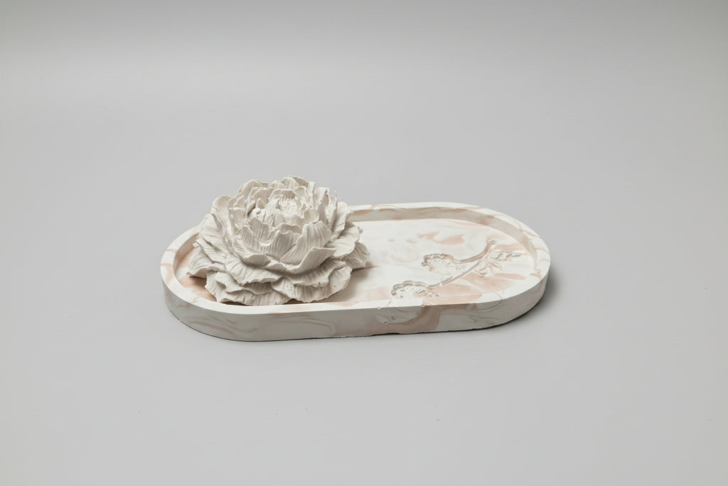 A white decorative floral sculpture on an oval tray.