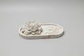 A white decorative floral sculpture on an oval tray.