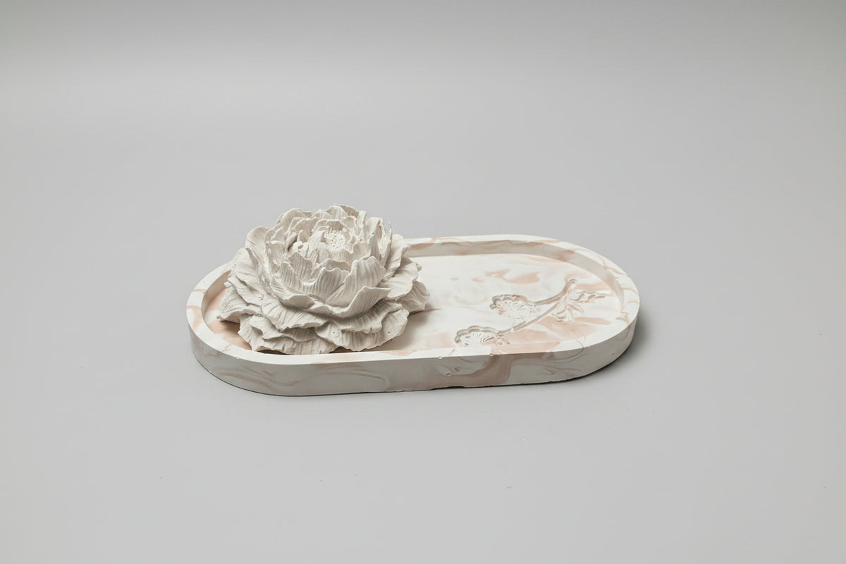 A white decorative floral sculpture on an oval tray.