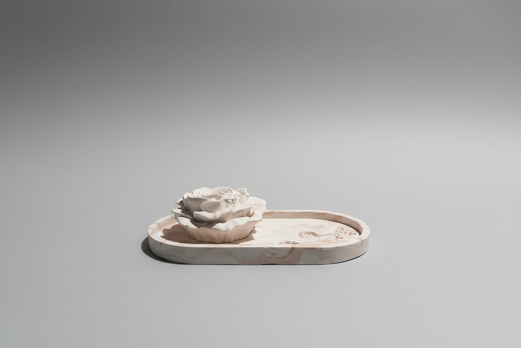 A handmade ceramic tray with a sculpted white rose on top.