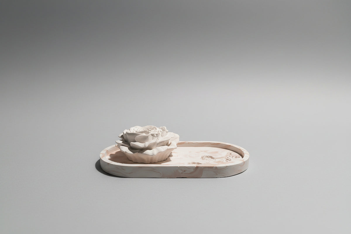 A handmade ceramic tray with a sculpted white rose on top.