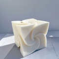 A sculptural, off-white foam block with a swirled, organic texture, photographed on a light gray surface with soft natural shadows.
